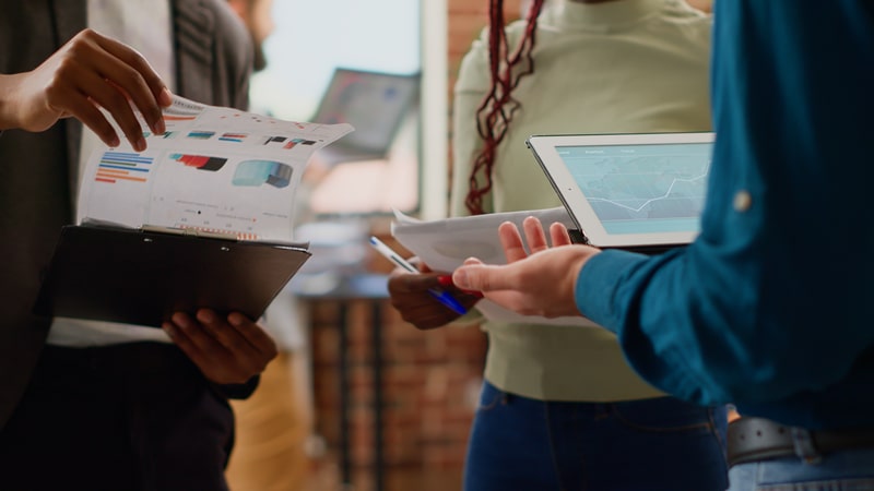 People looking at data reports on a paper and tablet.