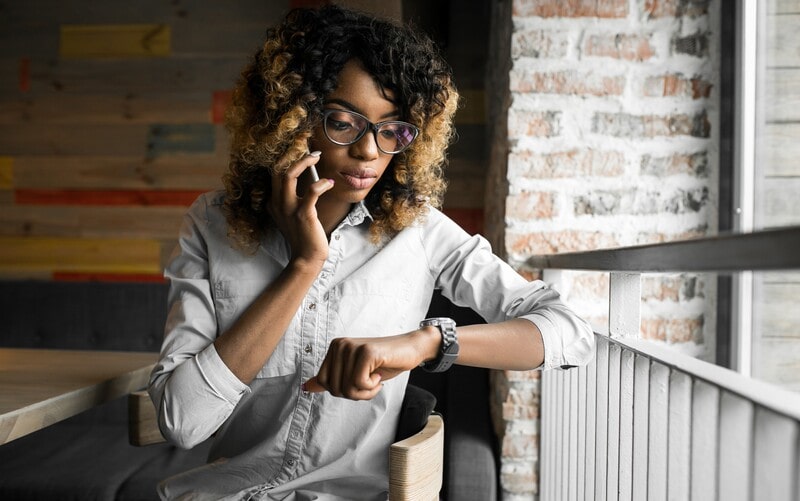 Alt text: An employee checking her watch while on a business call.