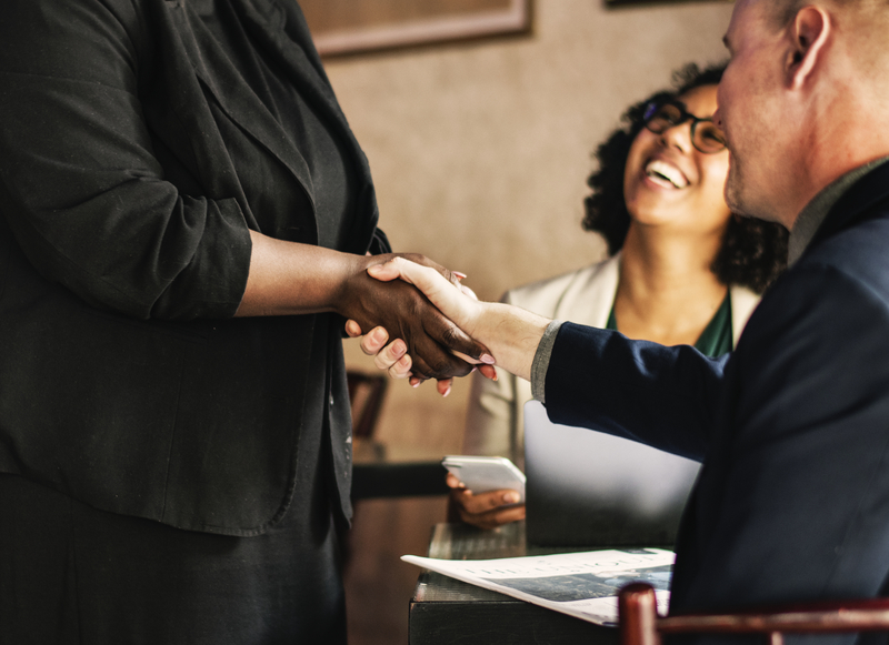 Franchisors shaking hands and smiling after a sales deal.