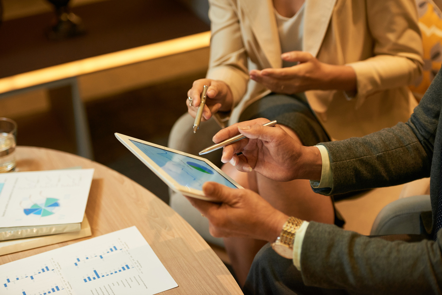 A pair of professionals discussing franchise systems on a tablet in an office setting.